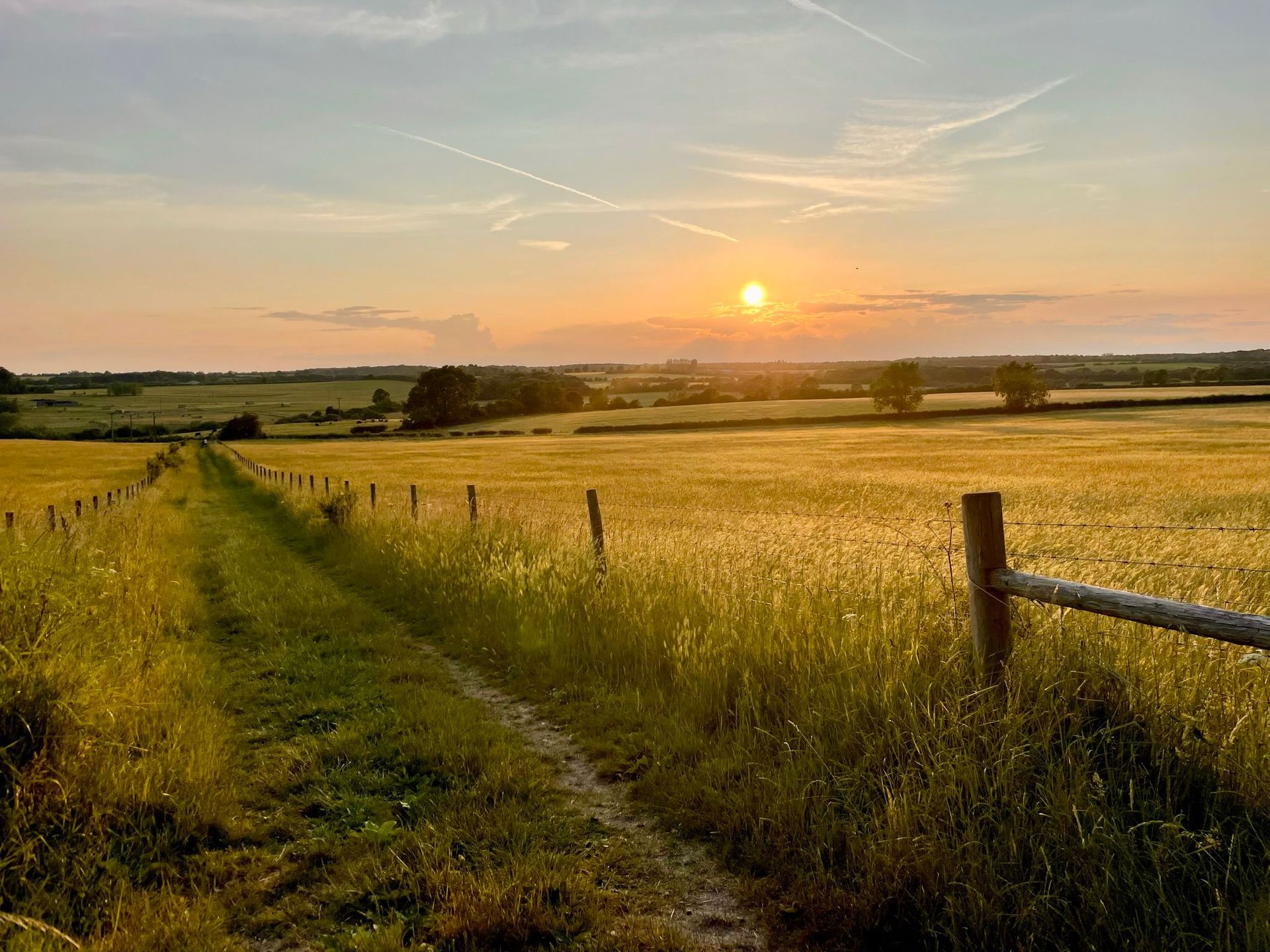 A golden sunset over the fields and barns on the edge of Olney